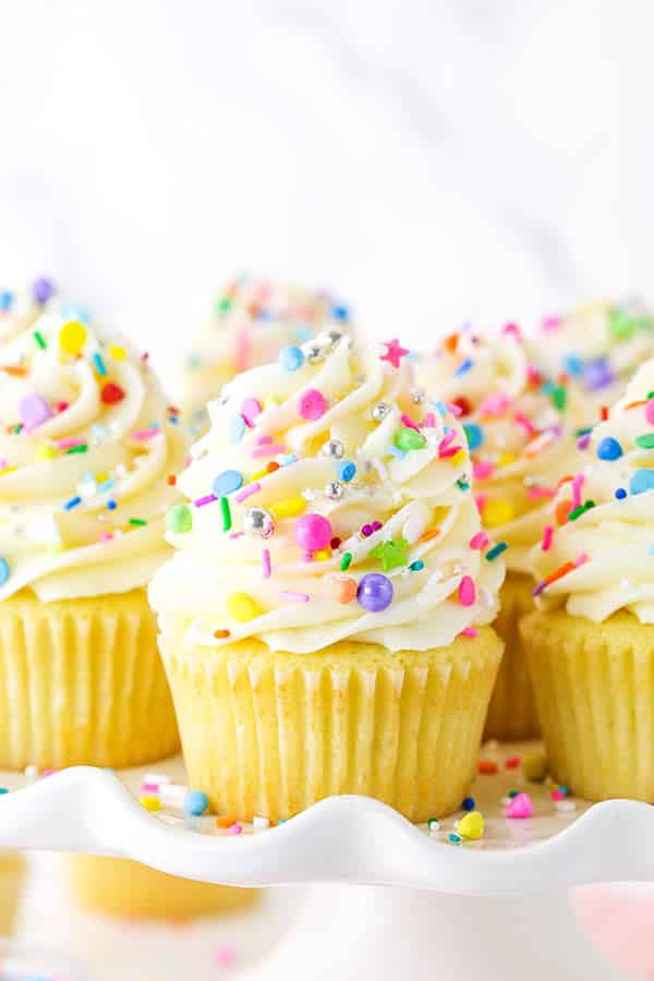 Pinterest image for vanilla cupcakes showing a close up of cupcakes and a stack of cupcakes on a white stand